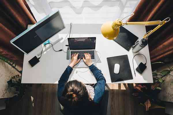 Frau sitzt im Homeoffice beim Schreibtisch und arbeitet am Laptop