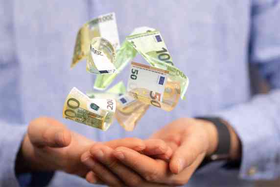 Hand mit schwebenden Geldscheinen